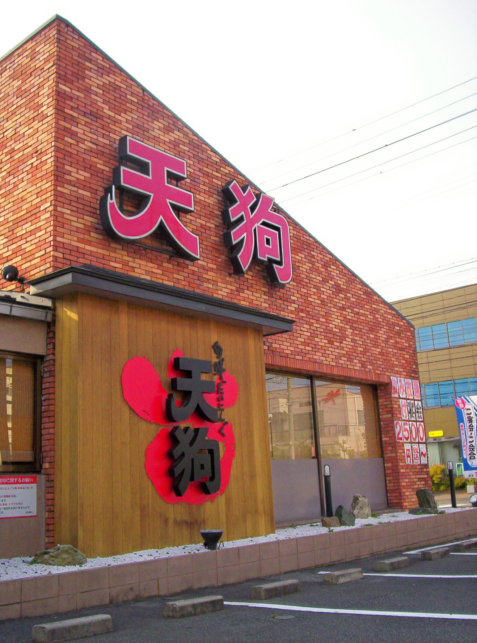 This restaurant is called "Tengu." Japanese Tengu are god-like beings that live on mountaintops. They are humanoid in form but can fly; they have bright red faces and very long noses. If you look carefully, you can see the outline of a Tengu face behind the lower set of characters.
